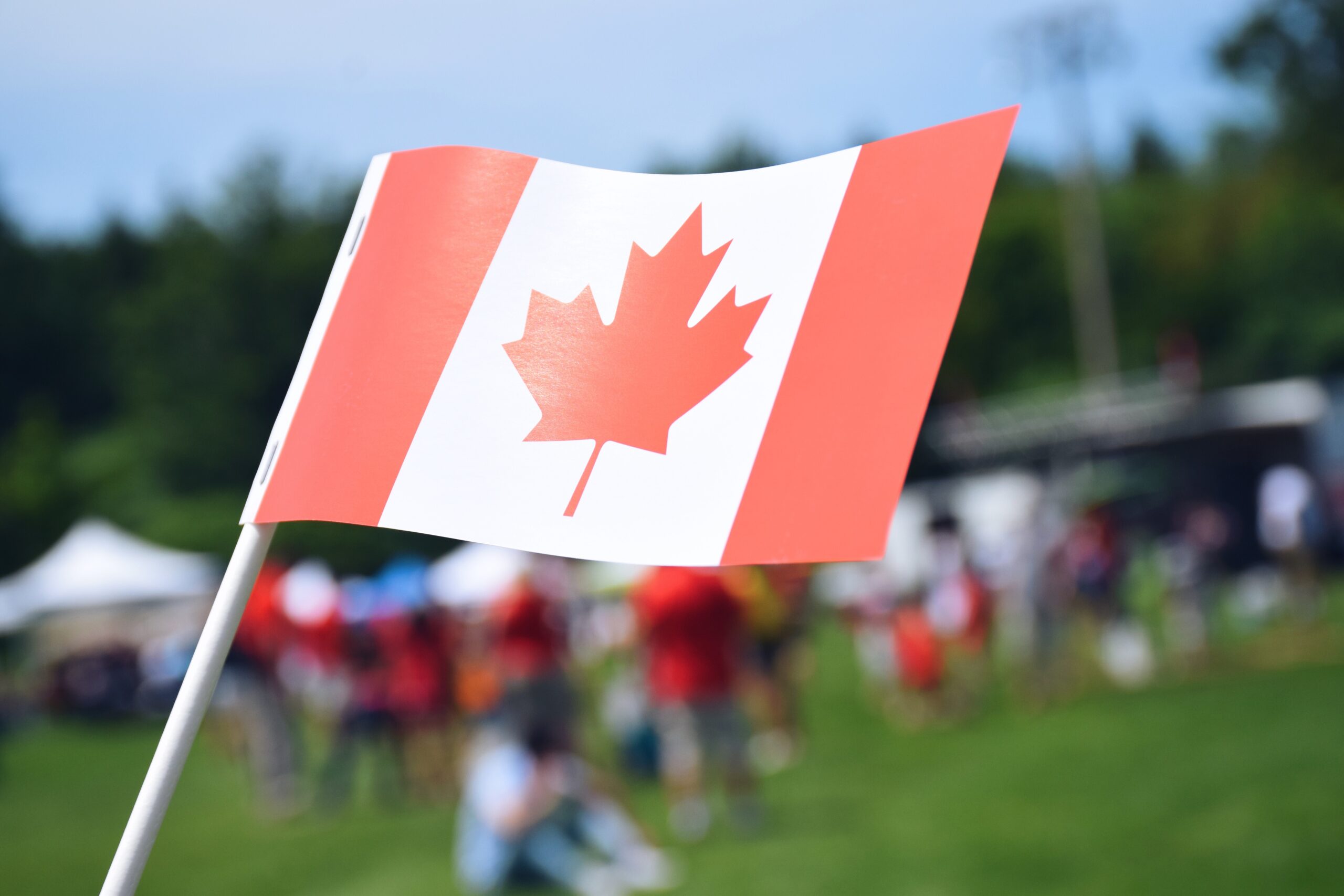 a-canadian-flag-with-blurred-fairgrounds-in-the-ba-2023-11-27-04-51-11-utc-scaled